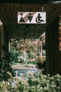 Facility staff inspect a clear wheelchair-accessible route, entrance, ramp, and restroom doorway.